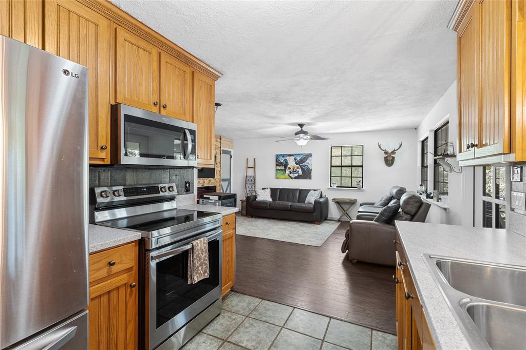 1069 Southeast Suwannee Trail Branford, FL 32008 - Photo 14 of 47 a kitchen with stainless steel appliances a stove a sink a refrigerator white cabinets and wooden floor