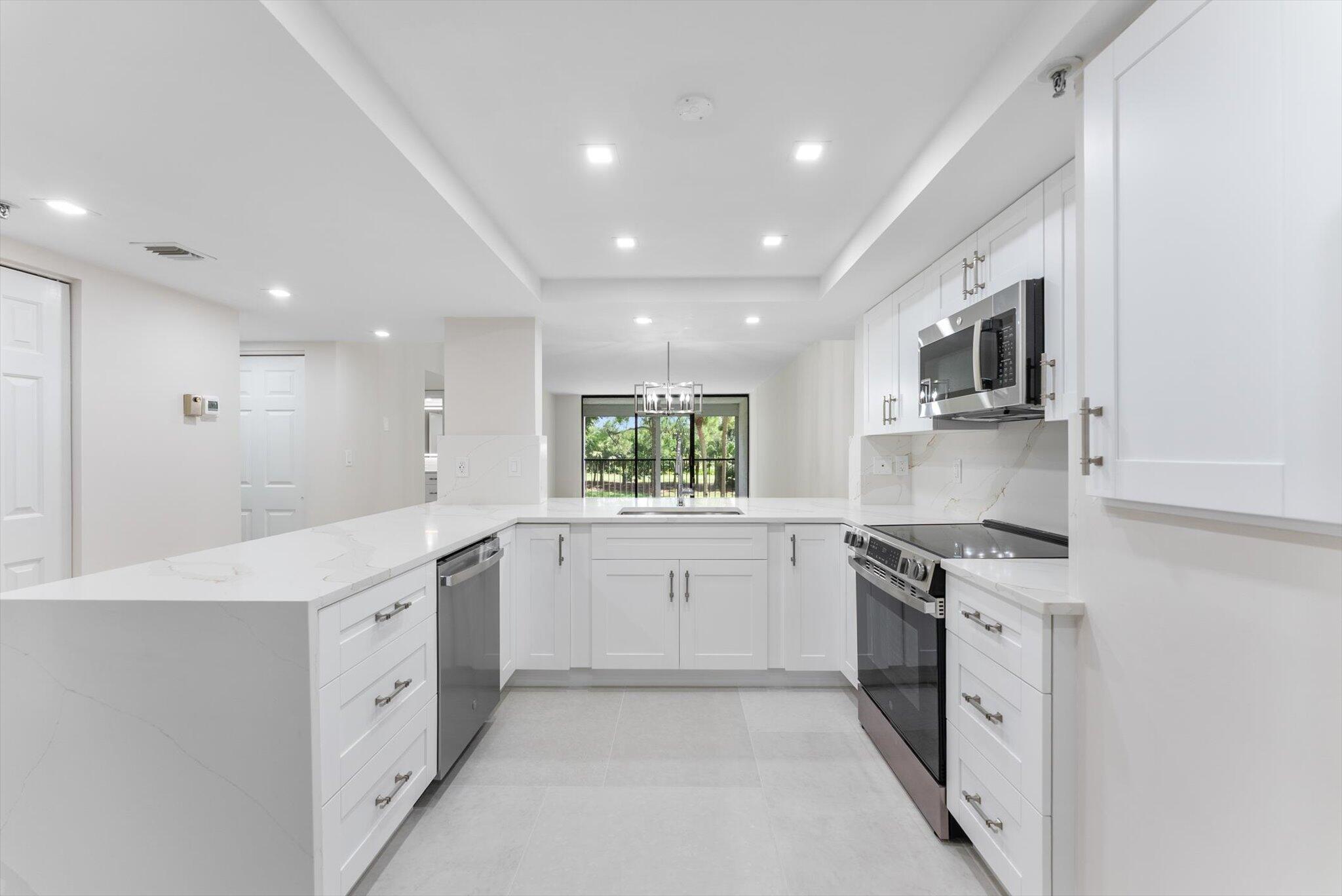 6562 Boca Del Mar Drive, Unit 222 Boca Raton, FL 33433 - Photo 7 of 39 a large white kitchen with stainless steel appliances granite countertop a stove a sink and a refrigerator