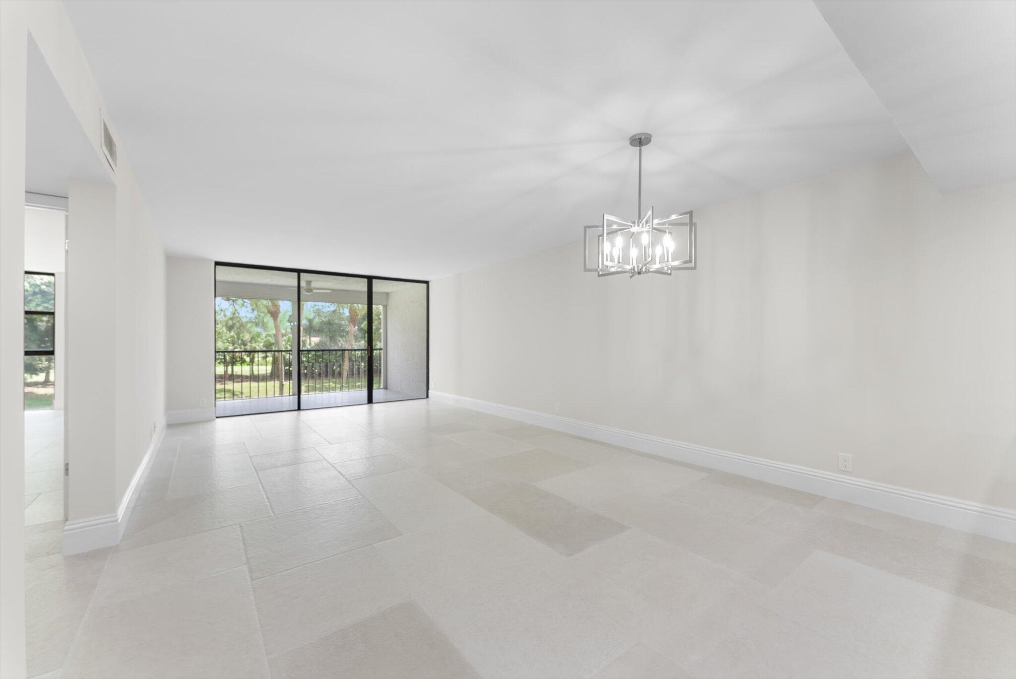 6562 Boca Del Mar Drive, Unit 222 Boca Raton, FL 33433 - Photo 8 of 39 an empty room with windows and chandelier