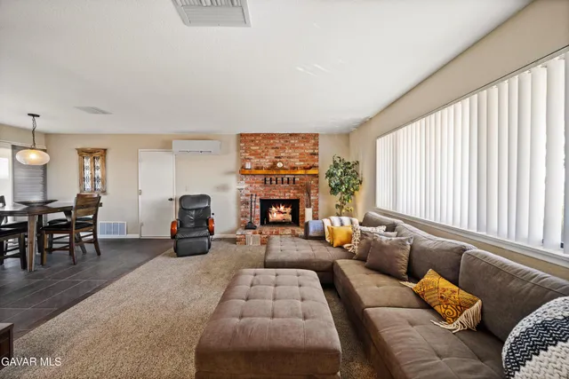 a living room with furniture two large window and a fireplace
