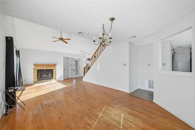a view of an empty room with a chandelier fan and a fireplace