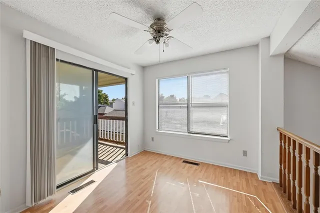 an empty room with chandelier fan and windows