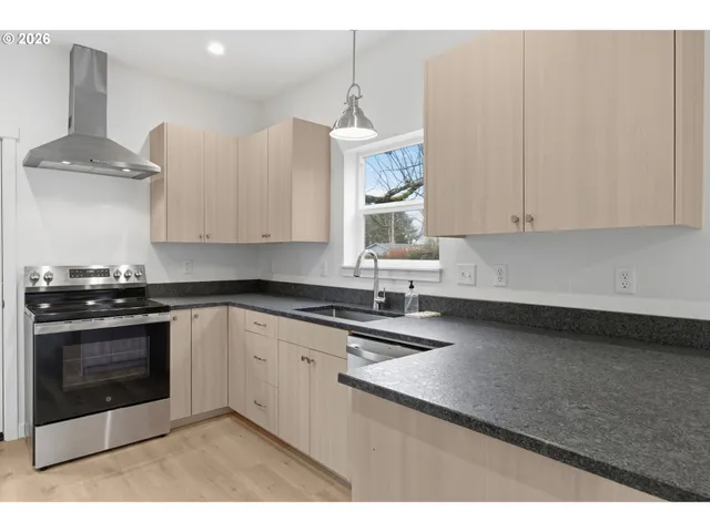 a kitchen with stainless steel appliances granite countertop a stove a sink and a white cabinets