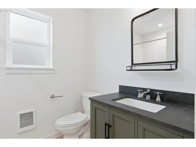 a bathroom with a granite countertop sink toilet and mirror