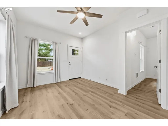 a view interior of a house with wooden floor a ceiling fan and windows