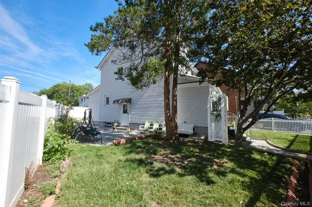 a backyard of a house with plants and large tree