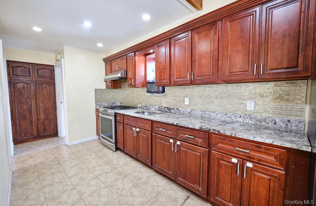 230-09 87th Avenue Queens, NY 11427 - Photo 5 of 22 a kitchen with stainless steel appliances granite countertop wooden cabinets a granite counter and a sink