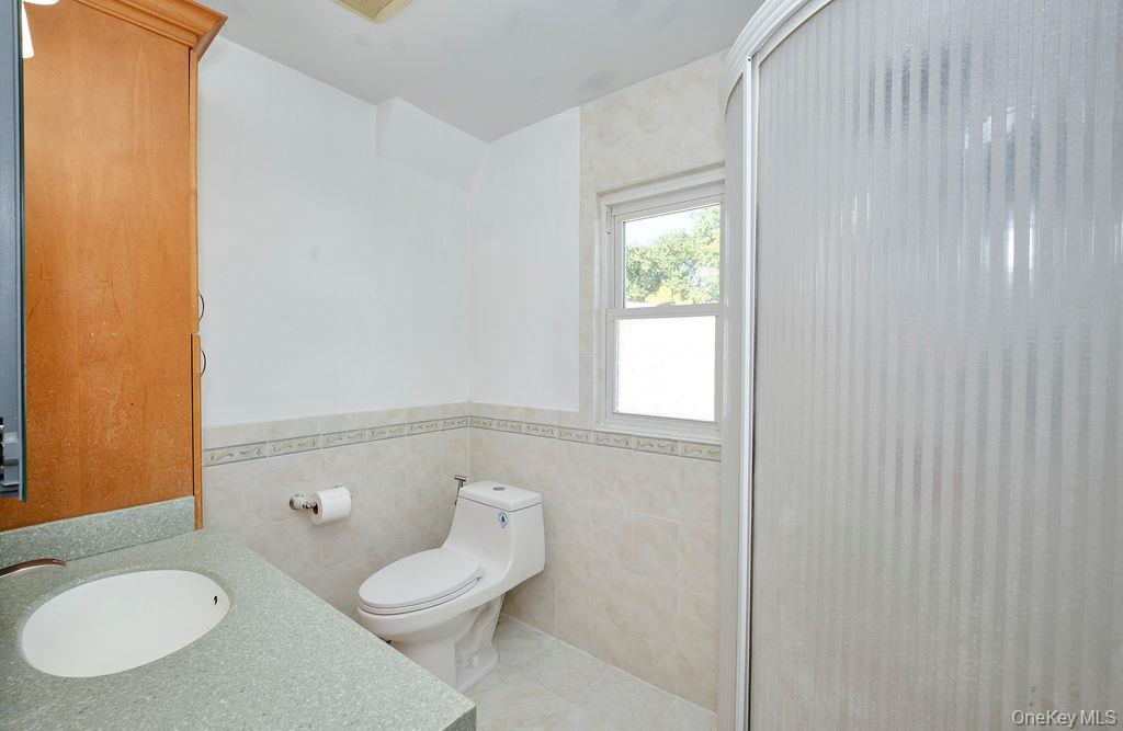 230-09 87th Avenue Queens, NY 11427 - Photo 7 of 22 a white toilet sitting next to a bathroom sink and vanity