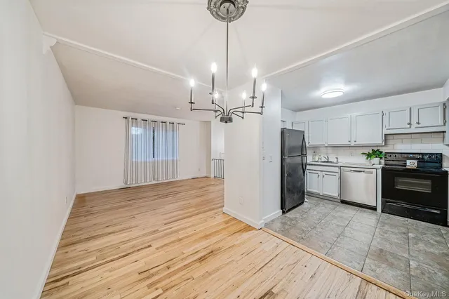 a kitchen with stainless steel appliances granite countertop a refrigerator a sink dishwasher a stove and white cabinets with wooden floor