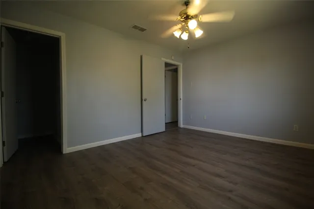 an empty room with wooden floor chandelier fan and closet area