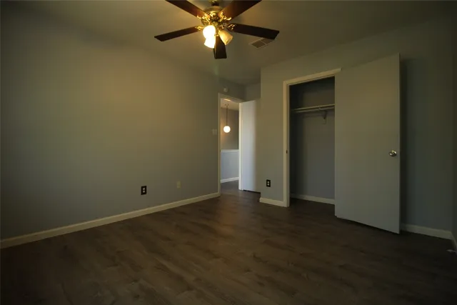 an empty room with wooden floor closet and fan