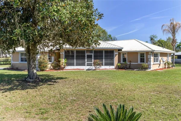 a view of a house with a backyard and a large tree