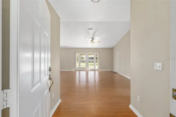 a view of an empty room with a window and wooden floor