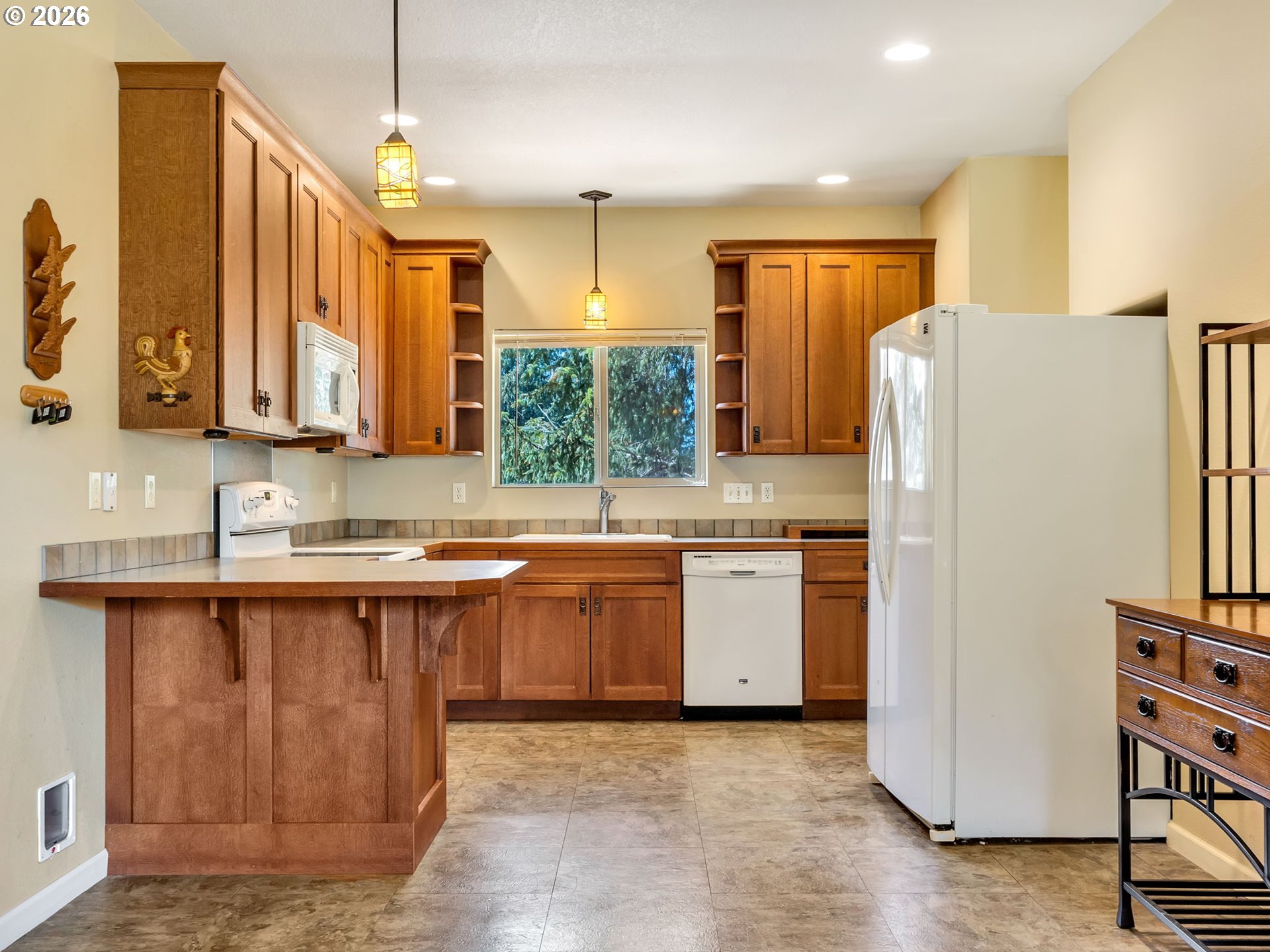 1077 Southwest Ridge Road Warrenton, OR 97146 - Photo 24 of 46 a kitchen with granite countertop a refrigerator a sink and white cabinets