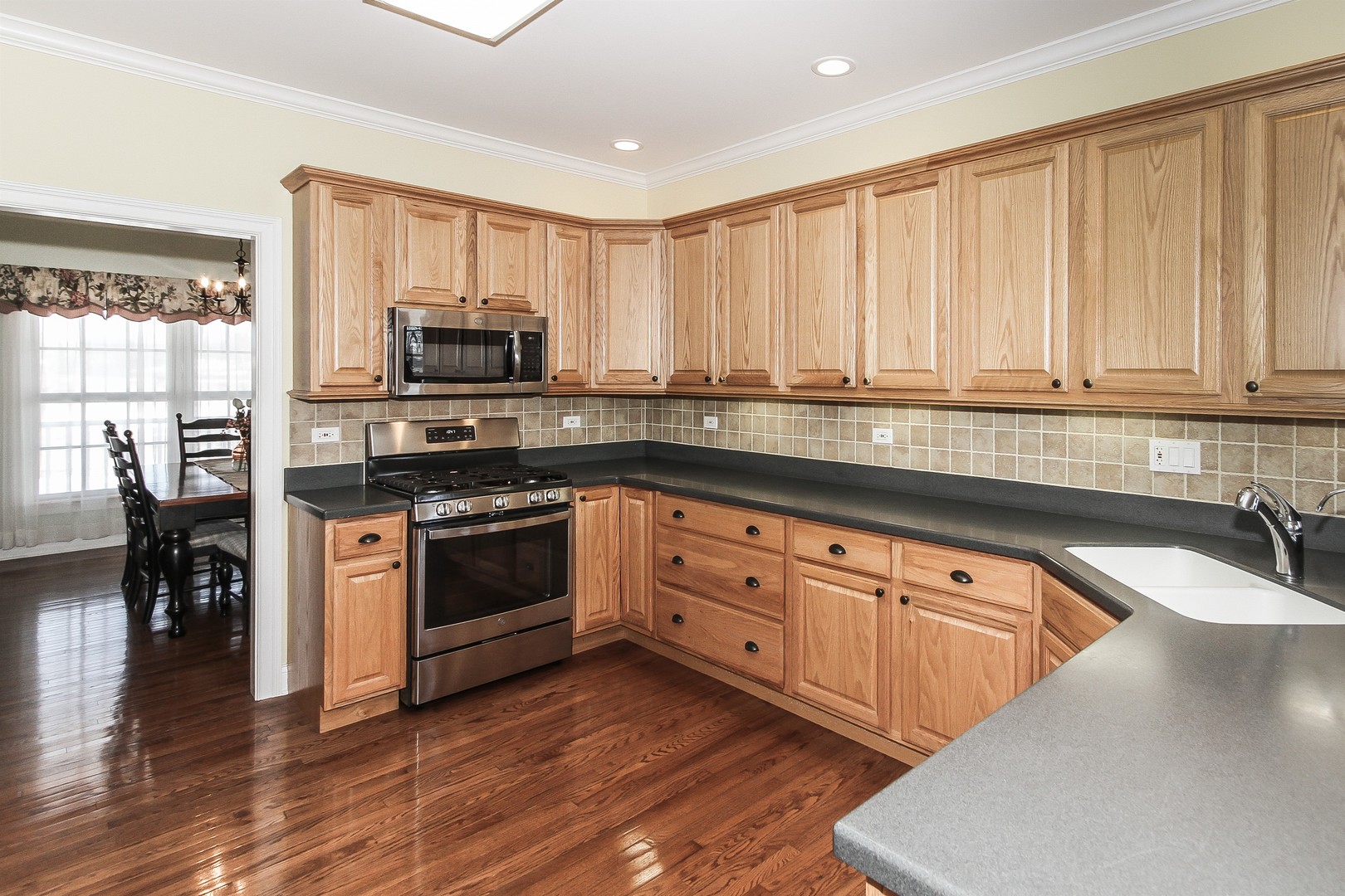 8762 Country Shire Lane Spring Grove, IL 60081 - Photo 9 of 39 a kitchen with stainless steel appliances granite countertop a stove a sink and a refrigerator