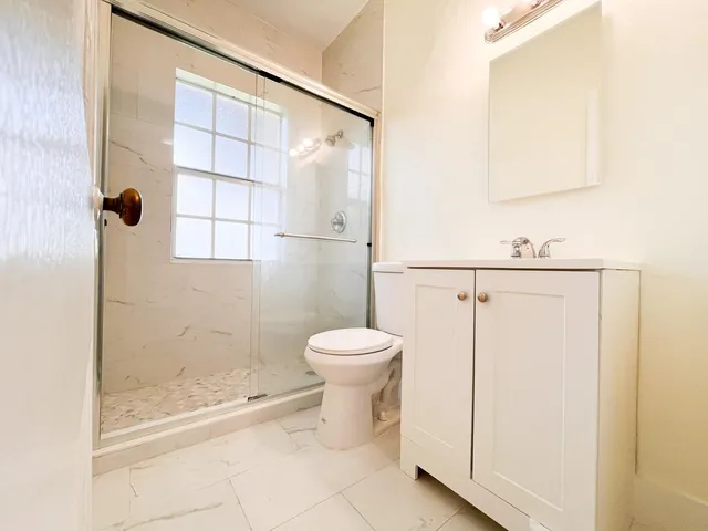 a bathroom with a granite countertop sink a toilet and shower