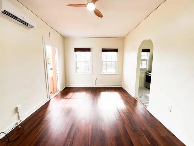 an empty room with wooden floor and windows