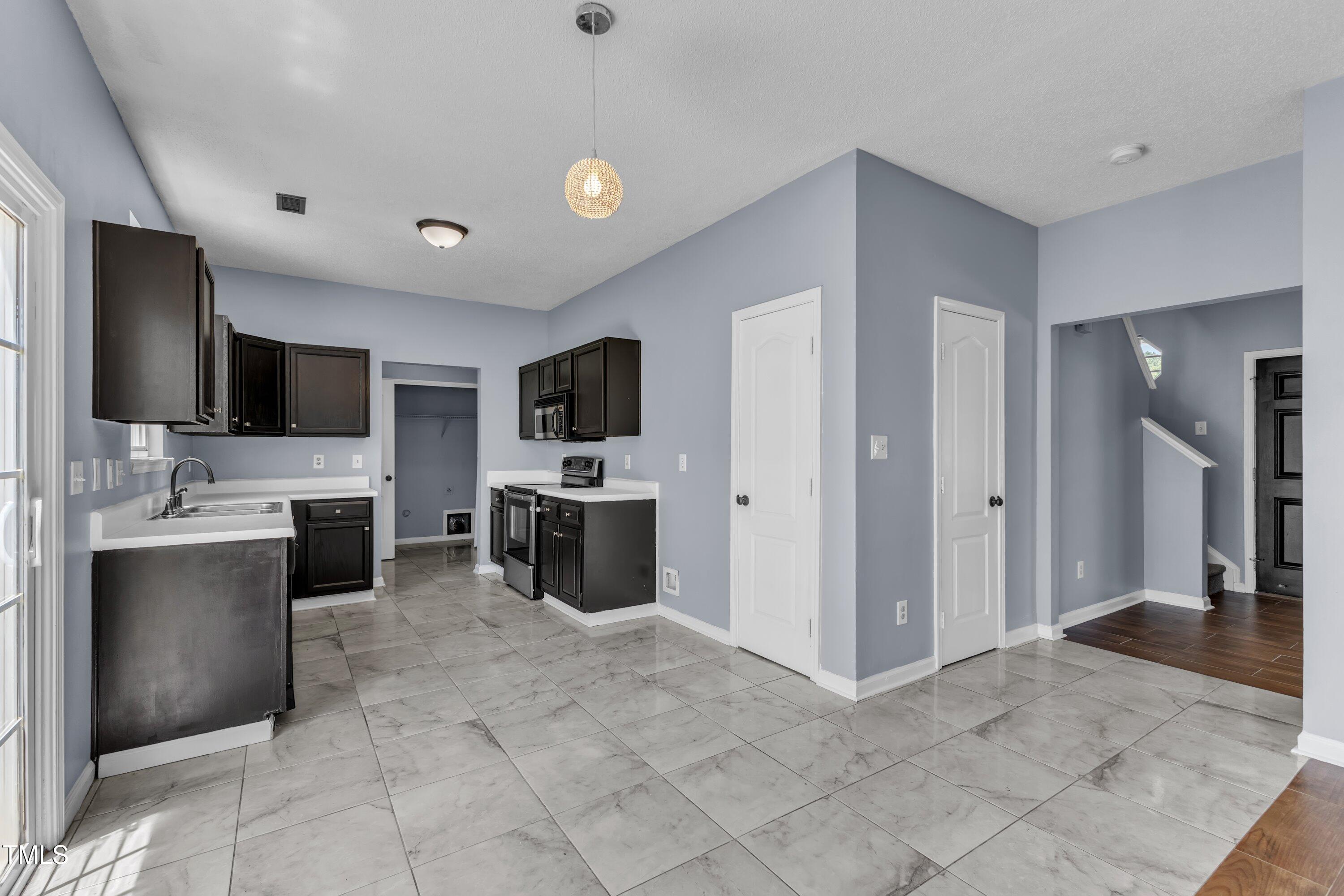 3604 Rivermist Drive Raleigh, NC 27610 - Photo 16 of 48 a view of living room kitchen with stainless steel appliances cabinets and flat screen tv
