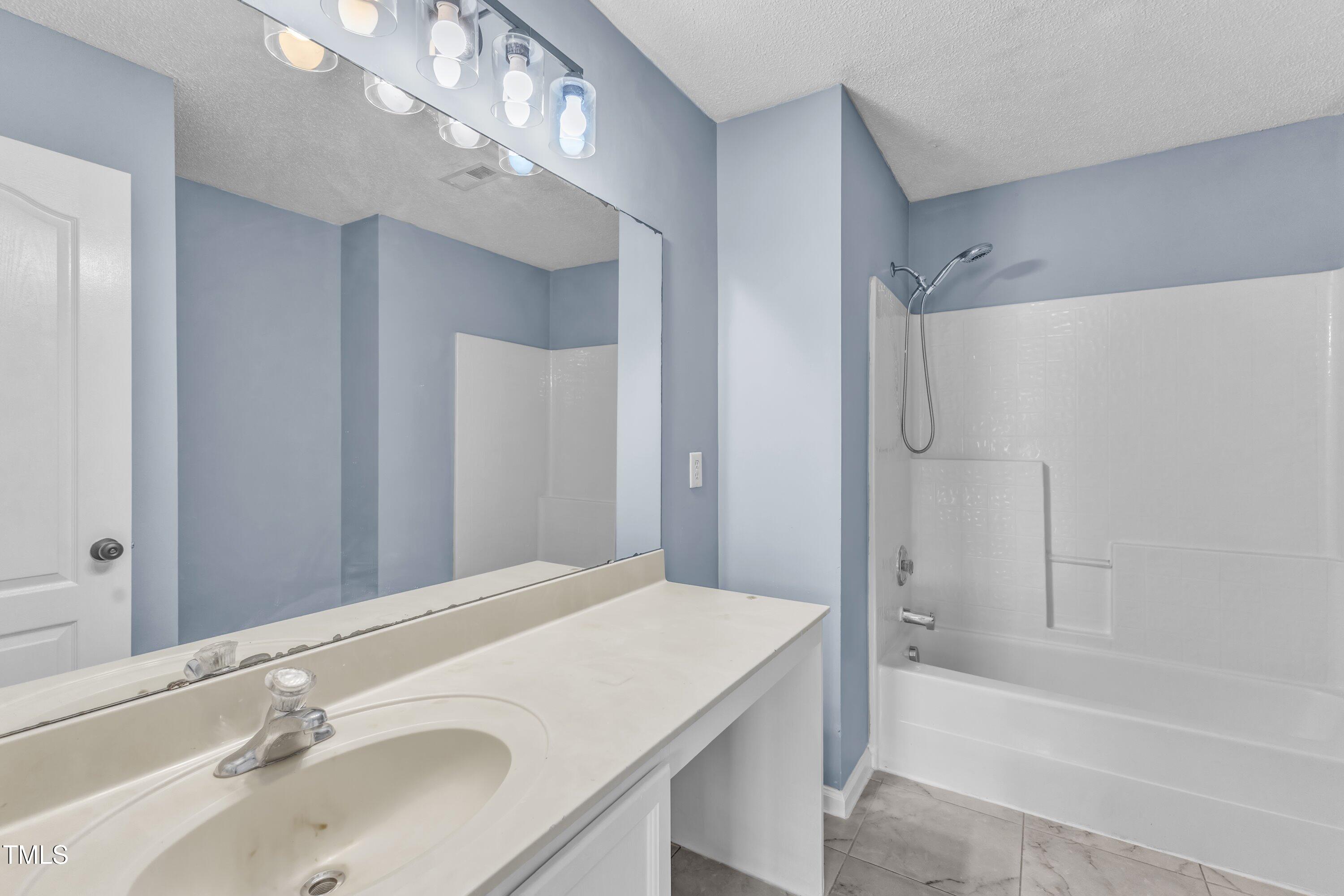 3604 Rivermist Drive Raleigh, NC 27610 - Photo 37 of 48 a bathroom with a sink a mirror and a bathtub
