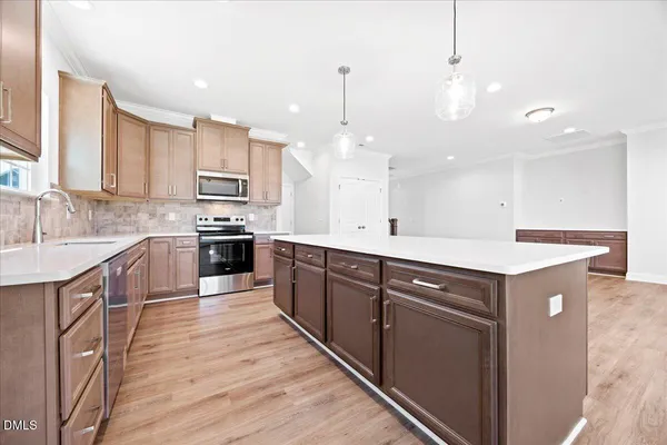 a large kitchen with stainless steel appliances kitchen island a large counter top a sink dishwasher a refrigerator and cabinets