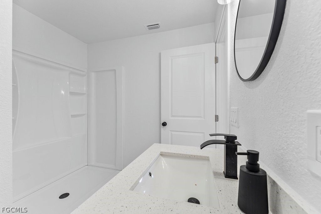 2512 42nd Street Southwest Lehigh Acres, FL 33976 - Photo 12 of 25 a bathroom with a tub a mirror and a shower