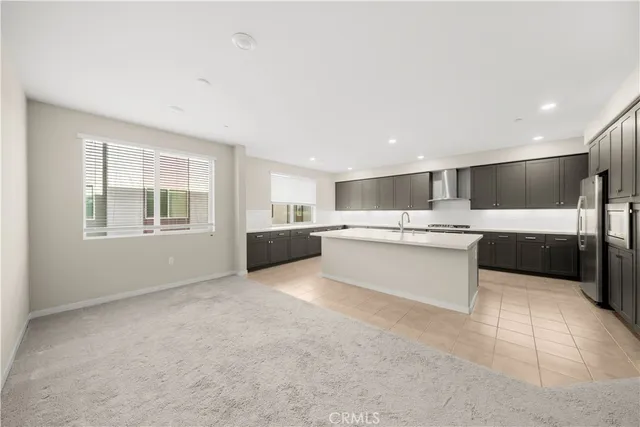 a large white kitchen with kitchen island a sink stainless steel appliances and cabinets