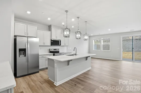 a kitchen with stainless steel appliances granite countertop a refrigerator a sink dishwasher a stove and white countertops with wooden floor