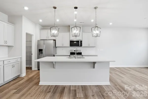 a large kitchen with granite countertop a sink cabinets and stainless steel appliances