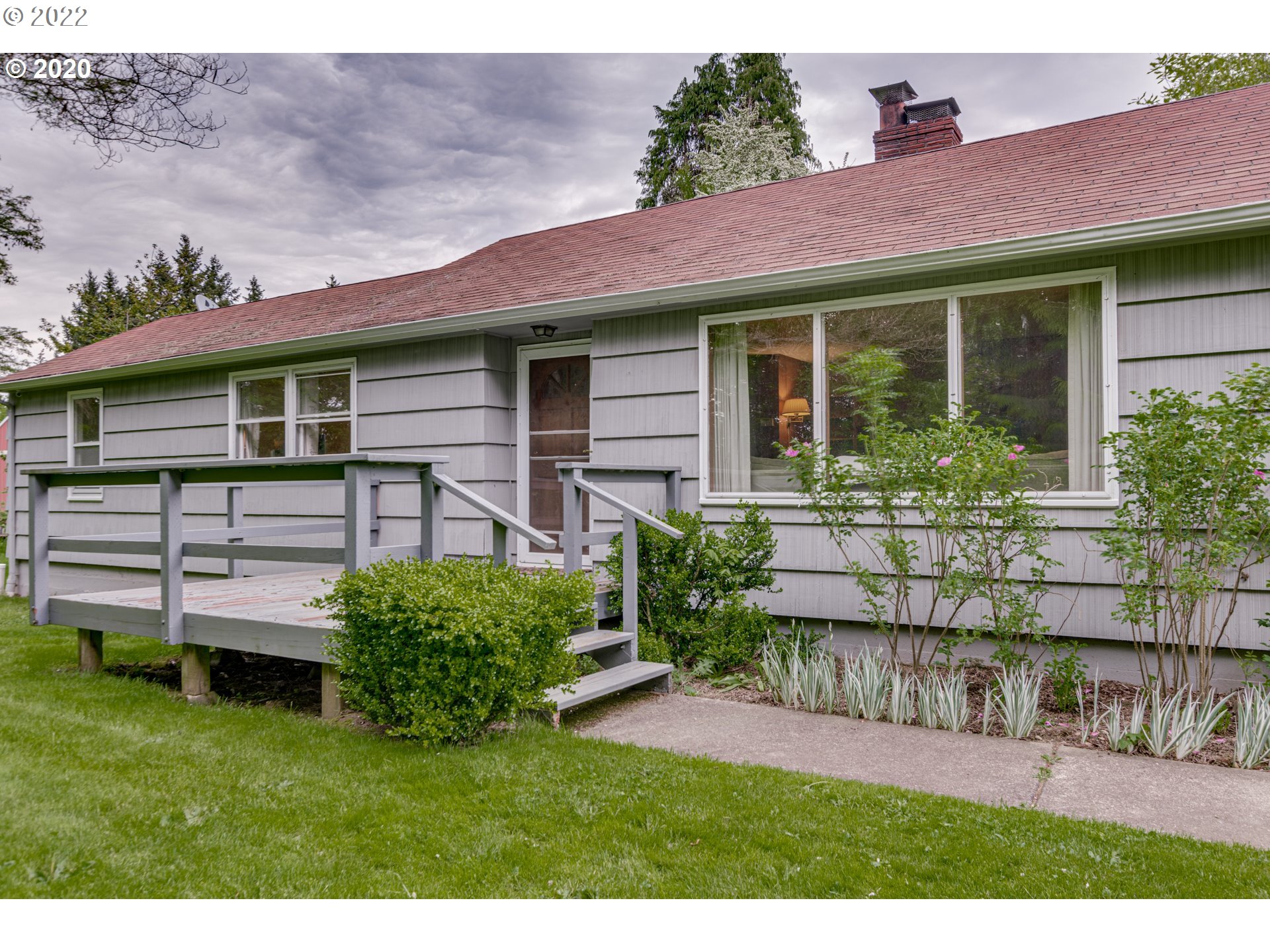 a front view of a house with a garden and plants