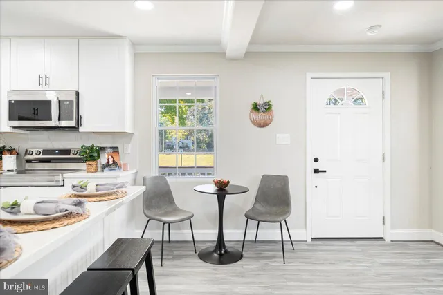 a kitchen with stainless steel appliances granite countertop a stove top oven a sink a dining table and chairs with wooden floor