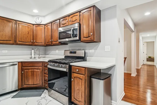 a kitchen with stainless steel appliances granite countertop a refrigerator a sink dishwasher and a stove