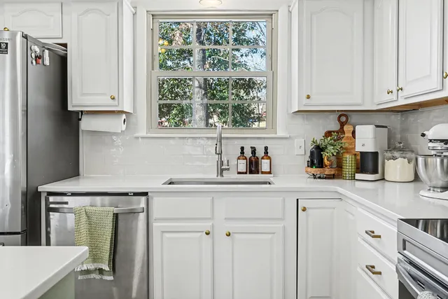 a kitchen with stainless steel appliances white cabinets and a window