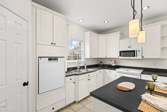 a kitchen with stainless steel appliances granite countertop a sink a stove a refrigerator and white cabinets