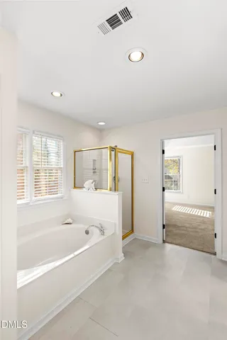 a white bath tub sitting in a spacious bathroom next to a window