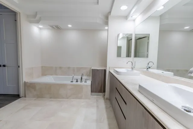 a bathroom with a tub double vanity sink and mirror