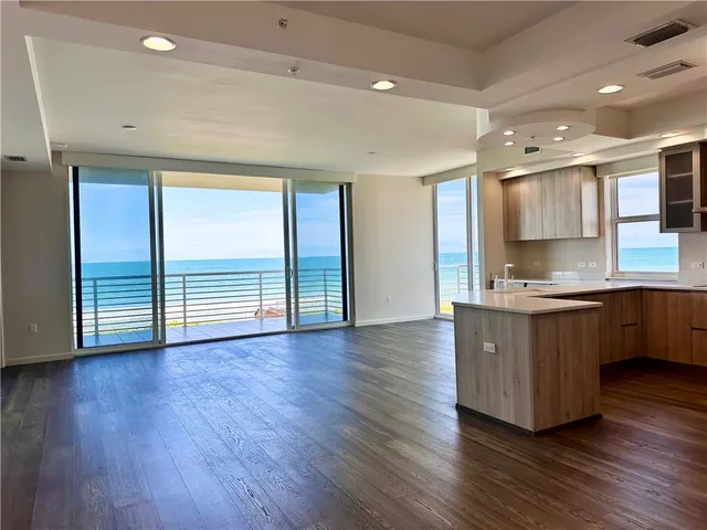 a large kitchen with a large counter top a sink stainless steel appliances and cabinets