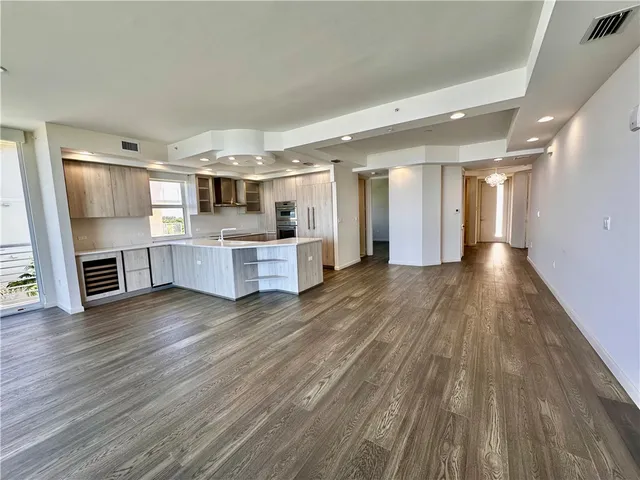 a view of a electric appliances in kitchen and empty room with wooden floor