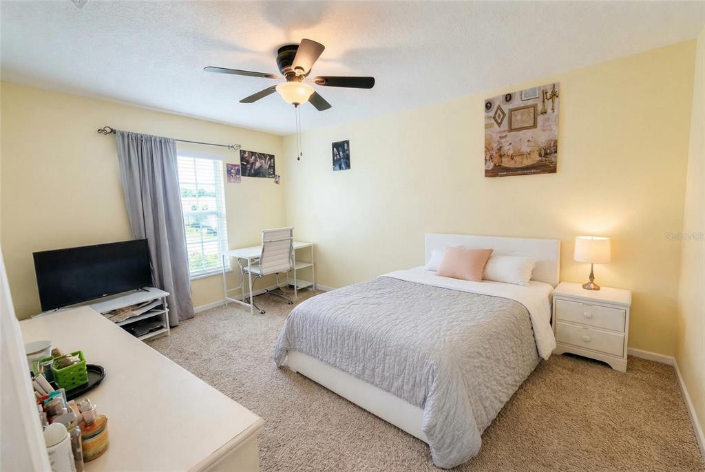217 Tres Reyes Lane Groveland, FL 34736 - Photo 14 of 20 a bedroom with a bed a computer on the desk and chair