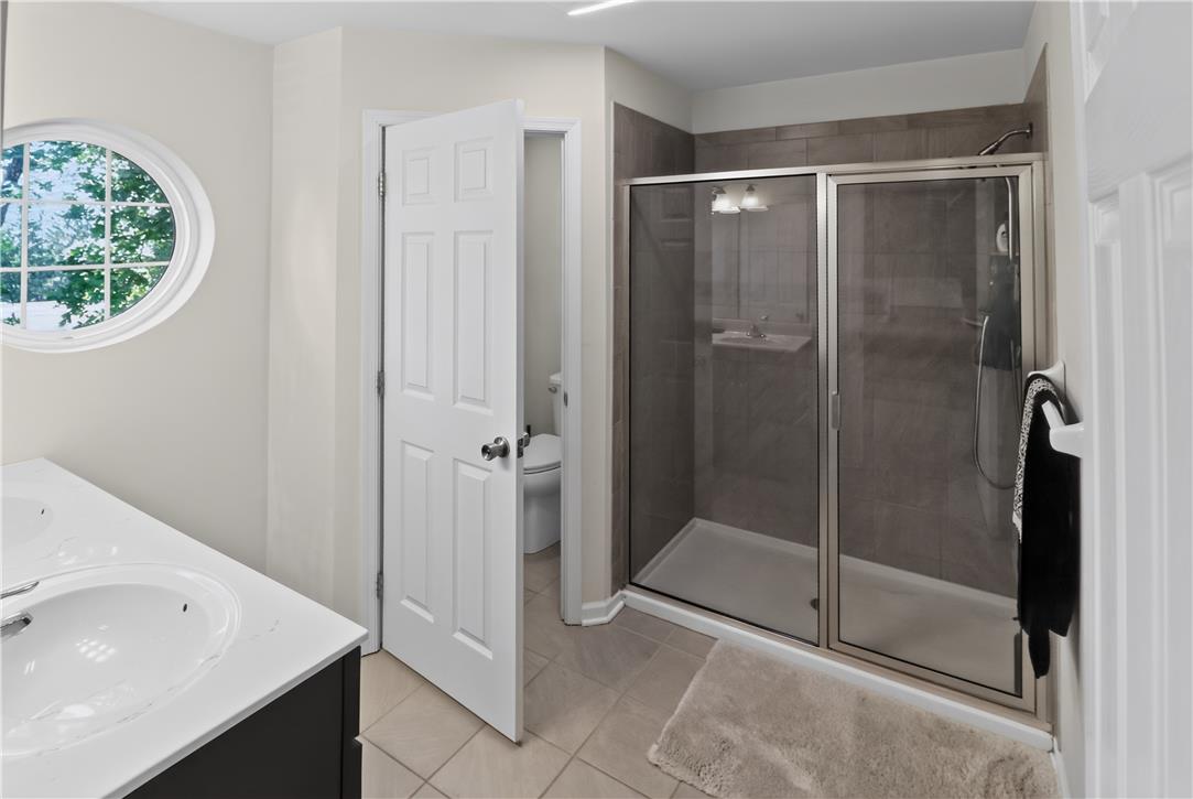 4502 Benjamin Court Emmaus, PA 18049 - Photo 28 of 48 A well-lit bathroom with a glass-enclosed shower and a striking circular window.