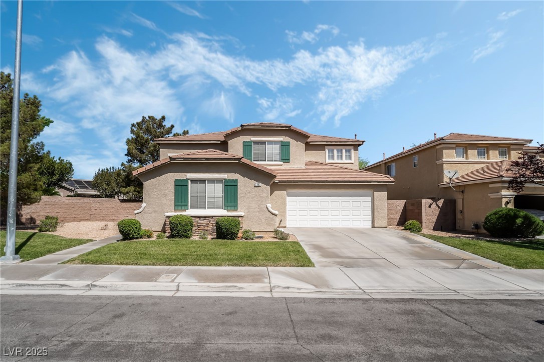 Traditional home with a tiled roof, driveway, an attached garage, a front yard, and stucco siding