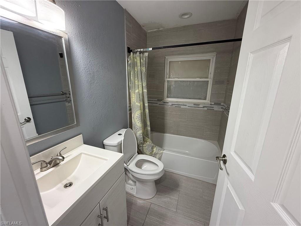 9169 Shaddock Road East Fort Myers, FL 33967 - Photo 6 of 8 Bathroom featuring a white vanity with integrated sink, brushed nickel faucet, tiled flooring, and a tiled shower surround with accent band