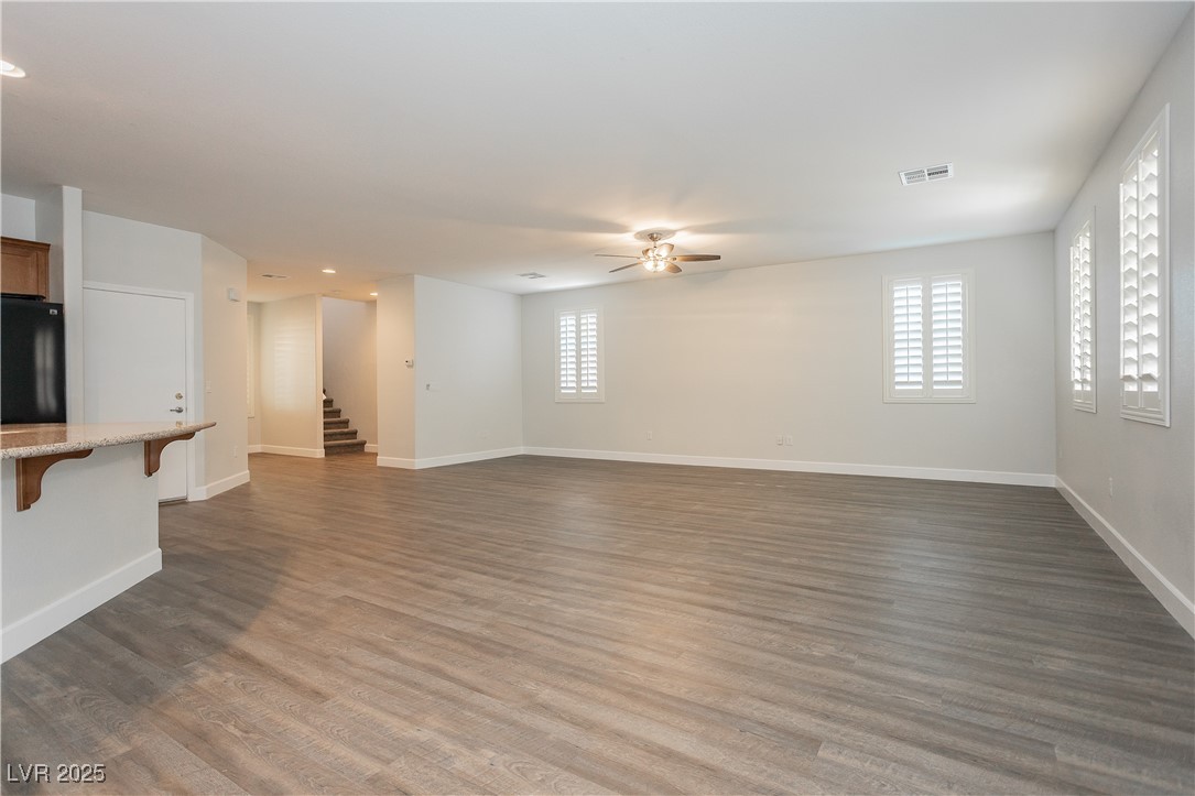 971 Huntington Cove Parkway Las Vegas, NV 89178 - Photo 14 of 55 Unfurnished living room featuring a ceiling fan, stairway, plenty of natural light, and dark wood-style flooring
