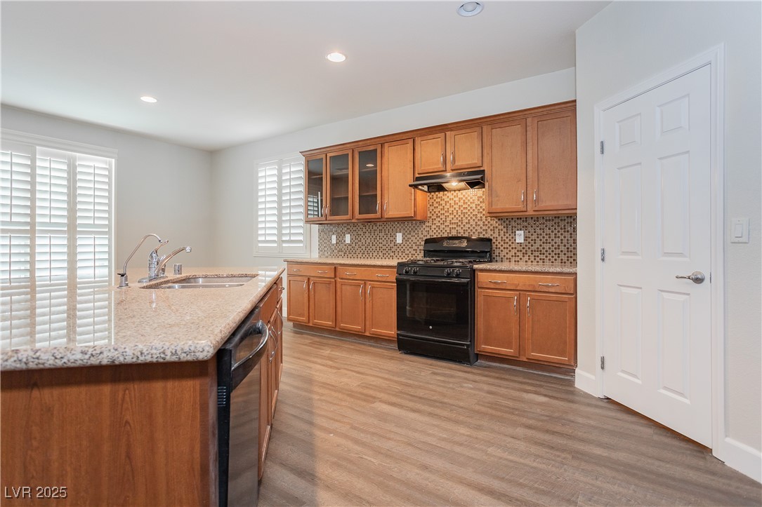 971 Huntington Cove Parkway Las Vegas, NV 89178 - Photo 15 of 55 Kitchen featuring black gas range oven, brown cabinetry, light wood finished floors, stainless steel dishwasher, and recessed lighting