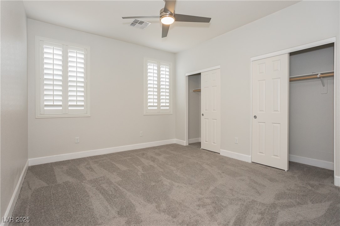 971 Huntington Cove Parkway Las Vegas, NV 89178 - Photo 29 of 55 Unfurnished bedroom with multiple closets, carpet, and ceiling fan
