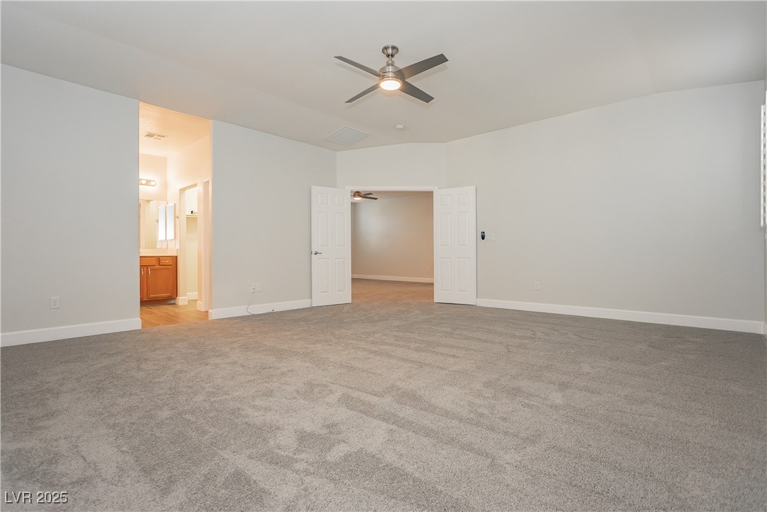 971 Huntington Cove Parkway Las Vegas, NV 89178 - Photo 41 of 55 Unfurnished bedroom with light colored carpet, a walk in closet, vaulted ceiling, ensuite bath, and a ceiling fan