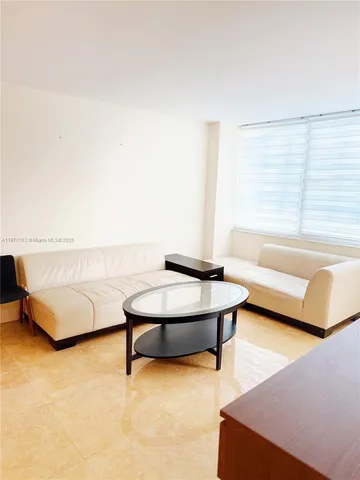 a living room with stainless steel appliances furniture a rug and a large window