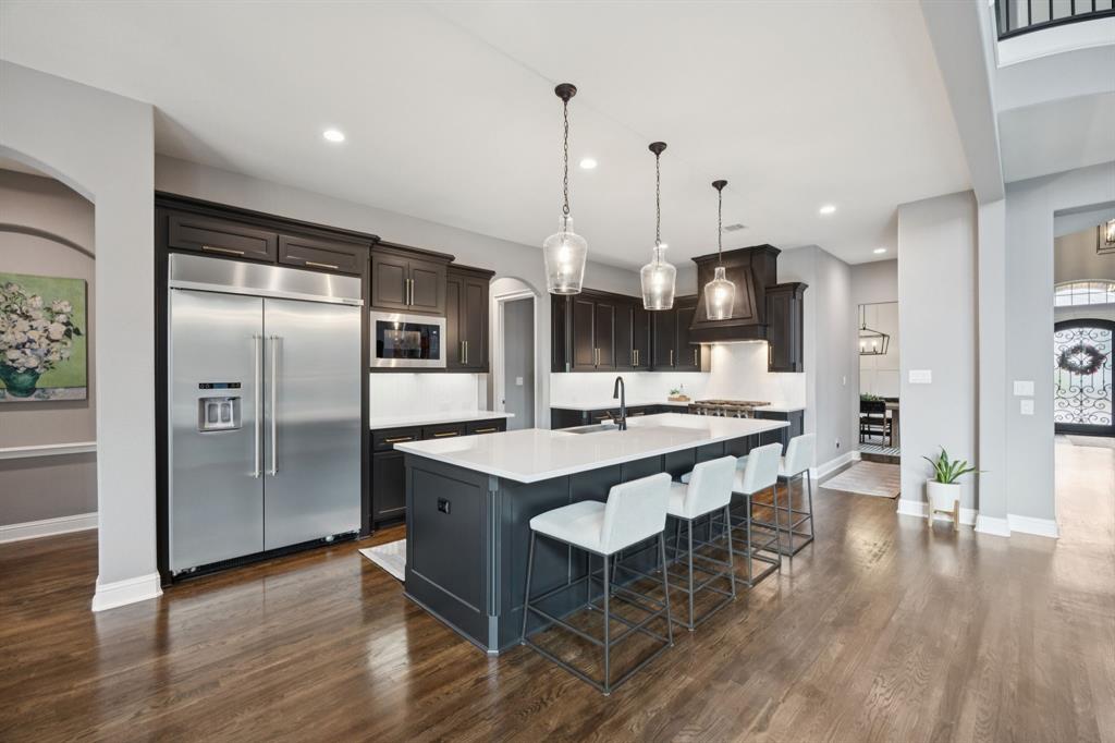 7121 Calypso Lane Frisco, TX 75036 - Photo 9 of 40 a kitchen with stainless steel appliances kitchen island granite countertop a refrigerator a stove a sink and a dining table with wooden floor