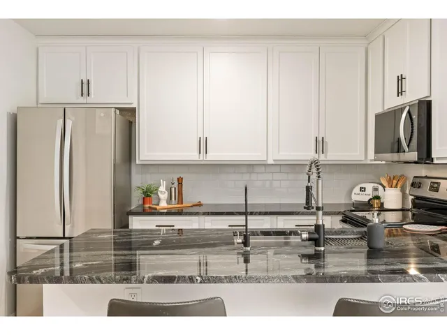 a kitchen with stainless steel appliances granite countertop a refrigerator a stove and a sink