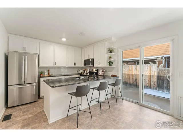 a kitchen with a refrigerator a sink dishwasher a dining table and chairs with wooden floor