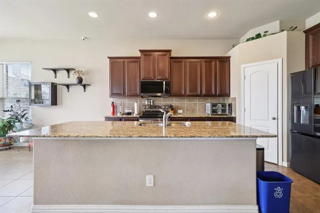 a kitchen with stainless steel appliances granite countertop a sink a refrigerator and a granite counter tops